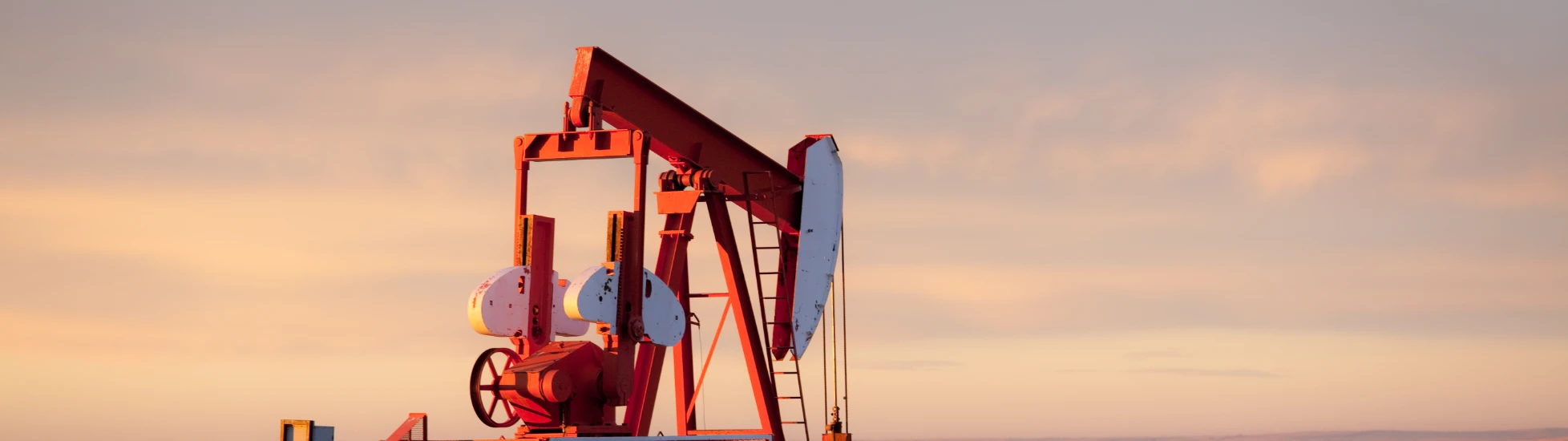 Pump jack in an oil field at sunset